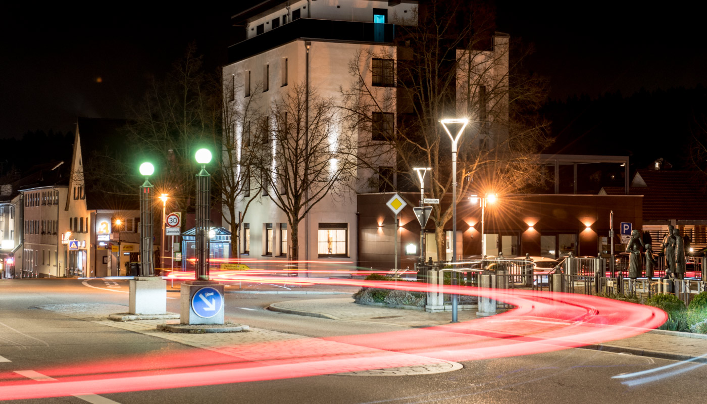 Nächtliche Straßenkreuzung mit Lichtspuren, Rundverkehr und beleuchteten Gebäuden in Birkenfeld